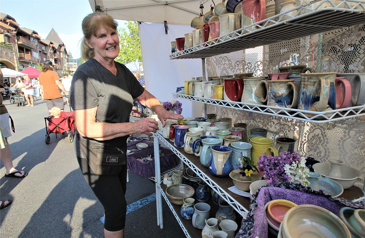 Bonnie Crain adjusts her pottery for sale at the Kootenai County Farmers' Market on Wednesday at Riverstone.