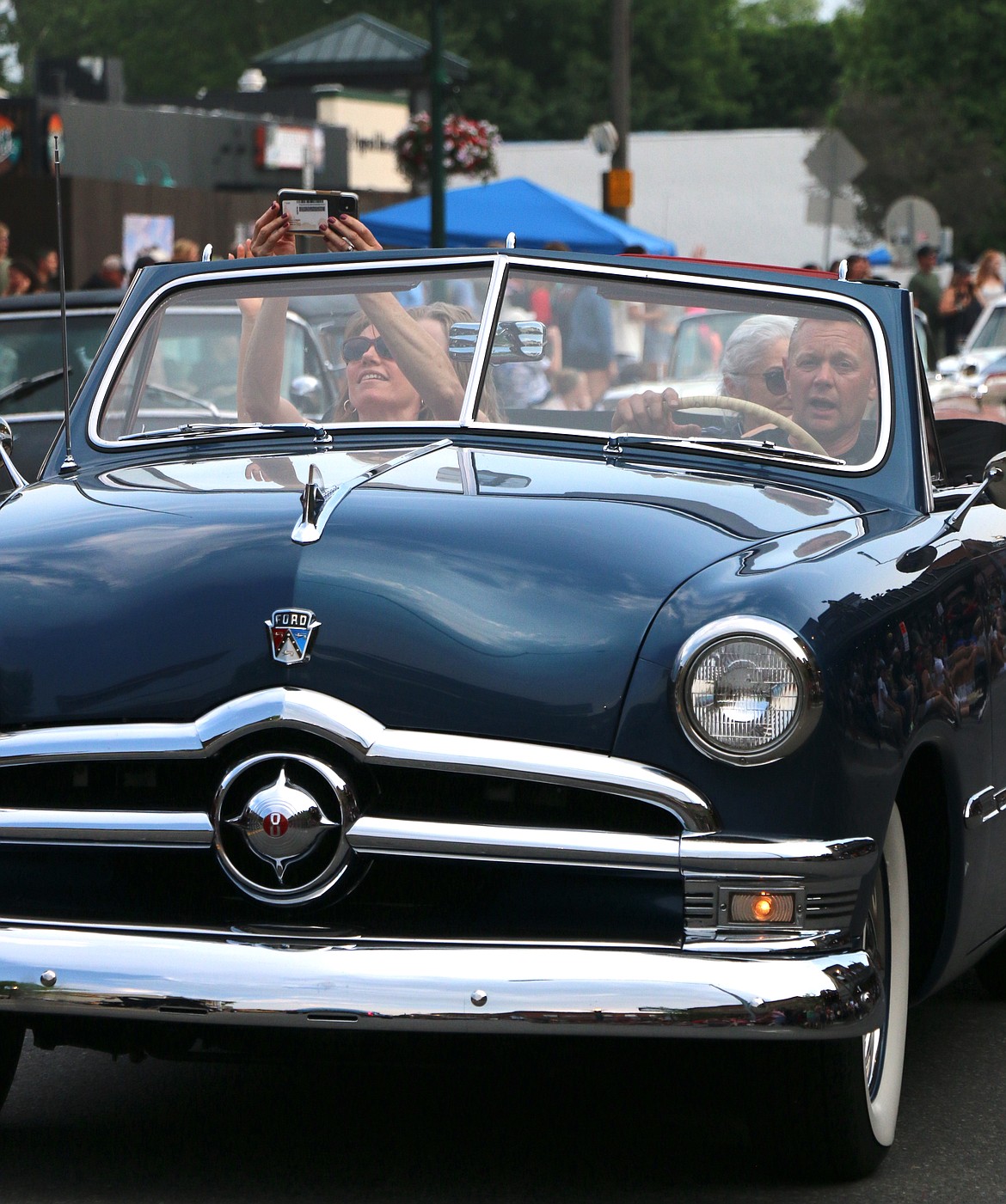 A Lost in the '50s car parade participants film the crowd from a classic ride as they make their way down First Avenue during the classic car parade on Friday night.