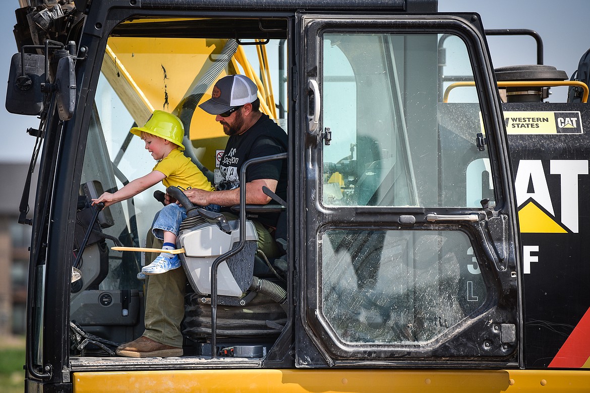 Malachi Elgersma works some of the controls inside an excavator with Cody Lee, of LHC, at the DIG Rotary event held by Kalispell Rotary Daybreak and Noon clubs at Rose Crossing and Highway 93 on Saturday, May 20. Attendees got the opportunity to operate excavators, bulldozers and graders with proceeds going toward the design and construction of a community splash pad along the Parkline Trail. (Casey Kreider/Daily Inter Lake)