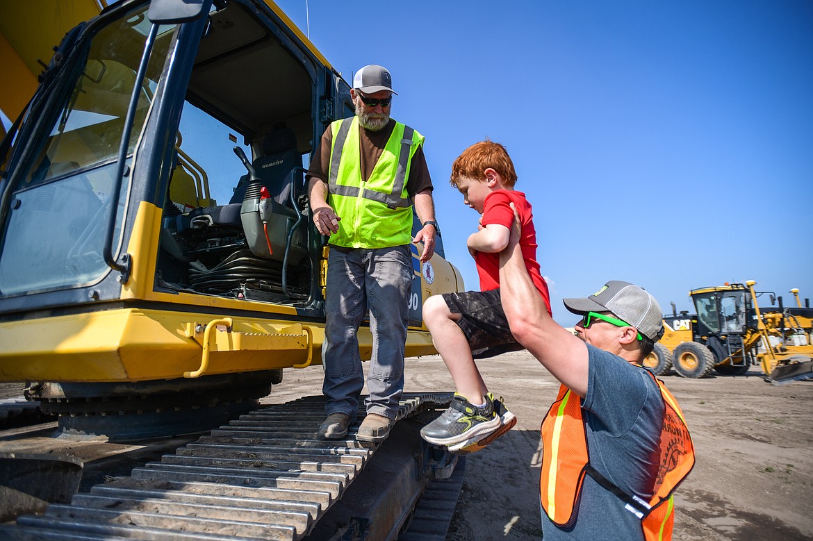 Volunteer Marty Flores hoists Levi Sanders up to Duane Moore, of Schellinger Construction at the DIG Rotary event held by Kalispell Rotary Daybreak and Noon clubs at Rose Crossing and Highway 93 on Saturday, May 20. Attendees got the opportunity to operate excavators, bulldozers and graders with proceeds going toward the design and construction of a community splash pad along the Parkline Trail. (Casey Kreider/Daily Inter Lake)