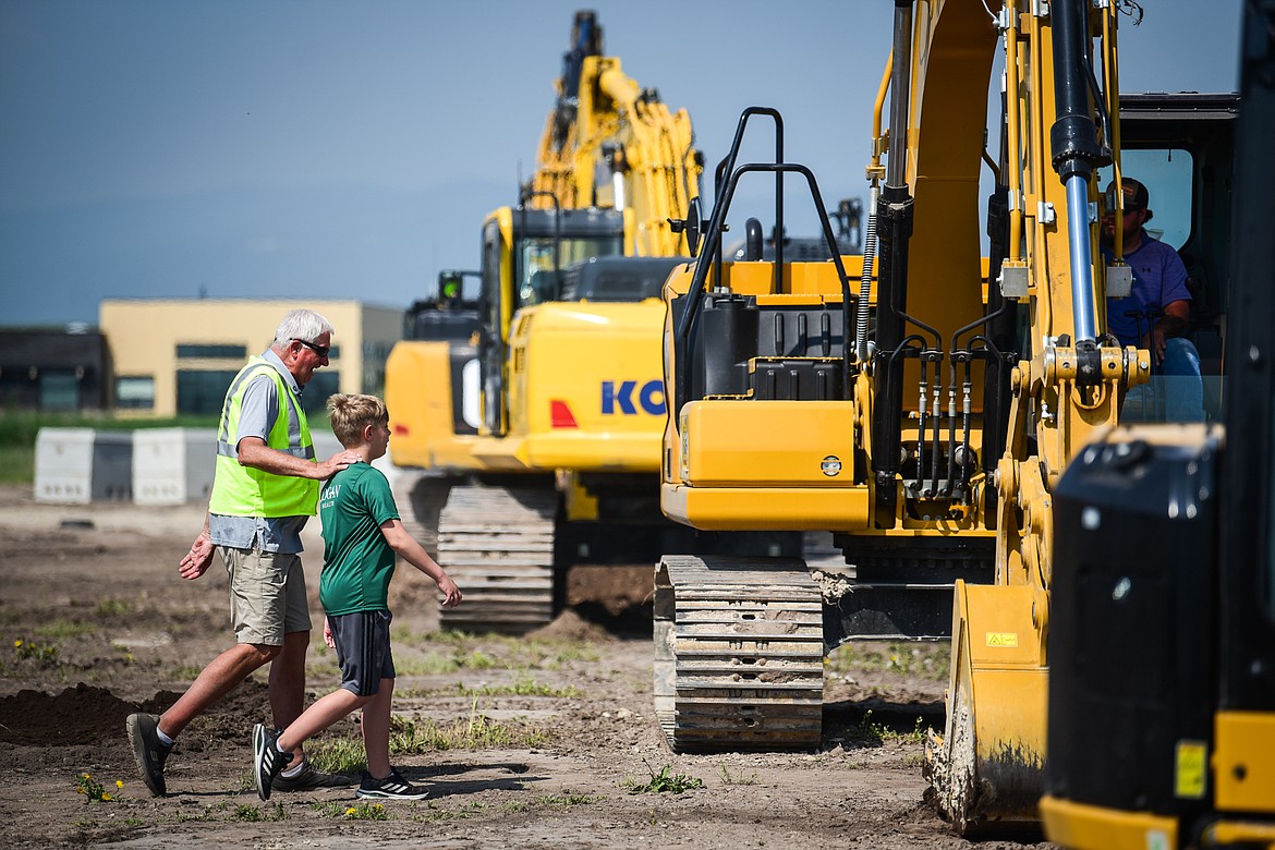 Volunteer Roy Beekman leads a child to an excavator at the DIG Rotary event held by Kalispell Rotary Daybreak and Noon clubs at Rose Crossing and Highway 93 on Saturday, May 20. Attendees got the opportunity to operate excavators, bulldozers and graders with proceeds going toward the design and construction of a community splash pad along the Parkline Trail. (Casey Kreider/Daily Inter Lake)