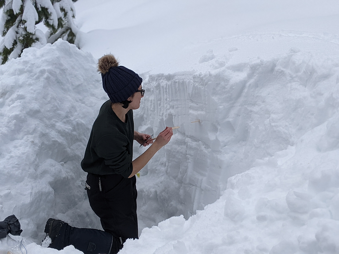 A young person practices snow science.