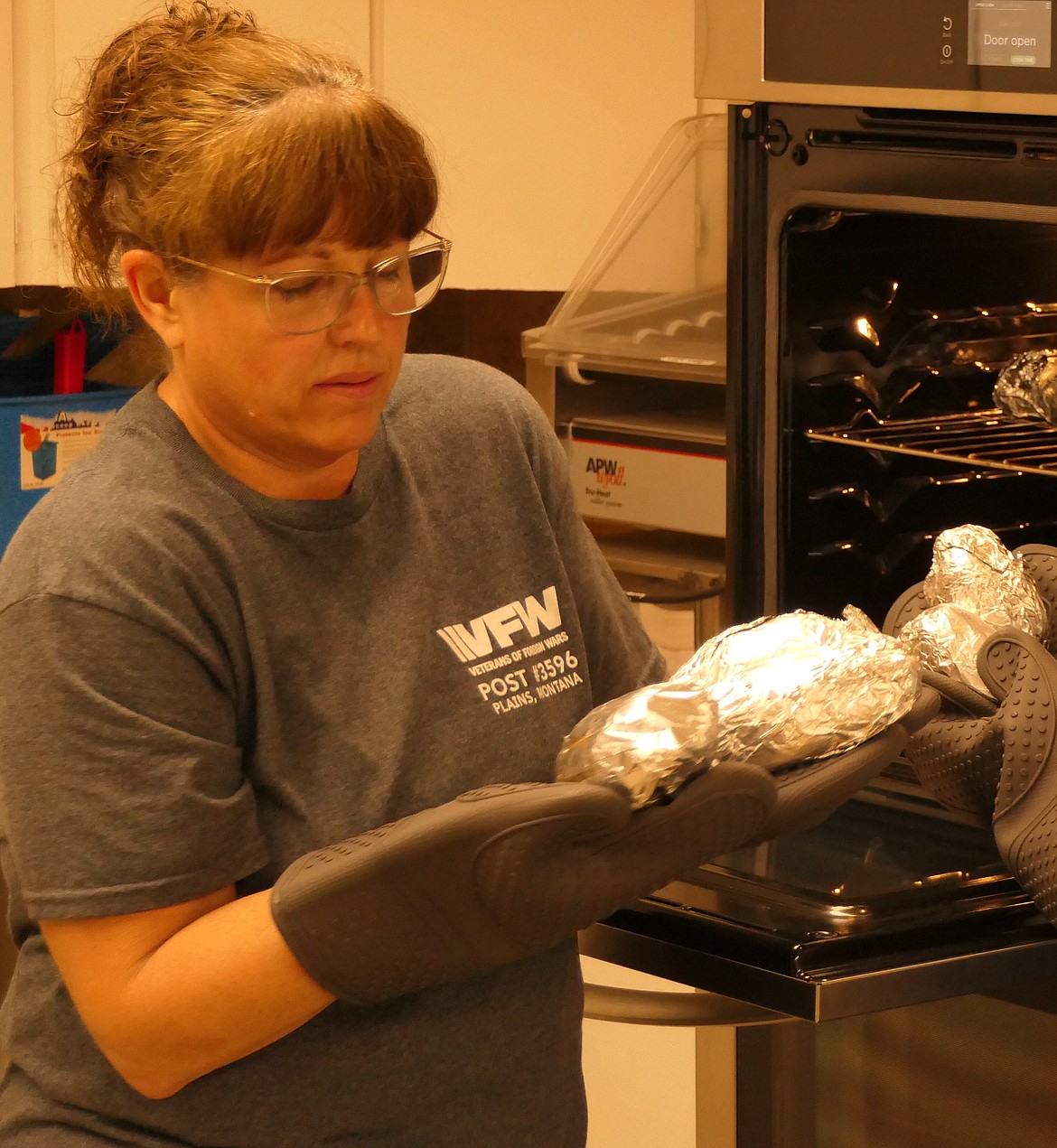 VFW Auxiliary member Angela Muse takes hot baked potatoes from the oven during the May Veterans Appreciation lunch last week at the Wild Horse Plains VFW. (Chuck Bandel/VP-MI)