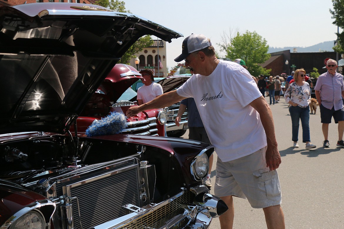 Dennis Hall brushes off the dust from his car in between talking to fans stopping to admire the car.