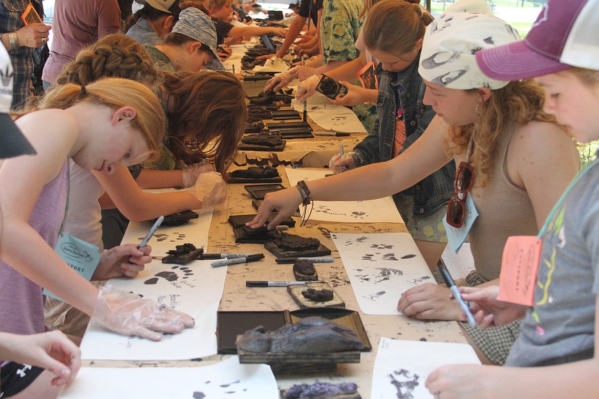 Washington Elementary School students work with high school student mentors to make bandanas at the animal tracks station