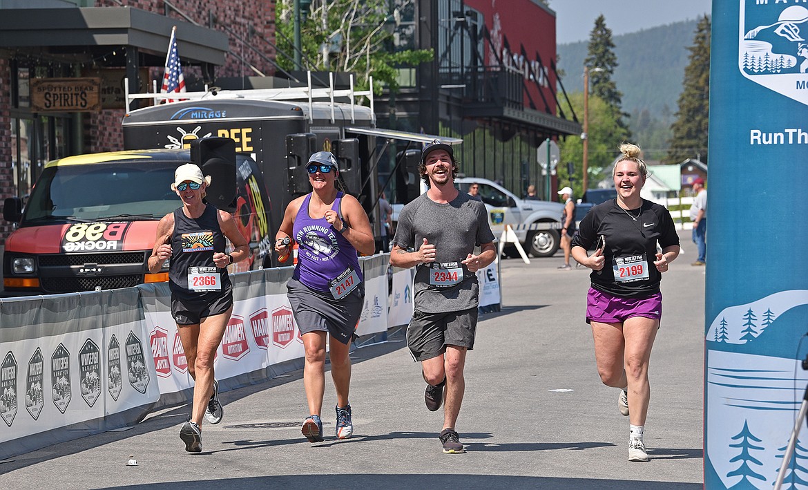 Four happy runners cross the finish line together after running the half marathon at Saturday's races in Whitefish. (Julie Engler/Whitefish Pilot)