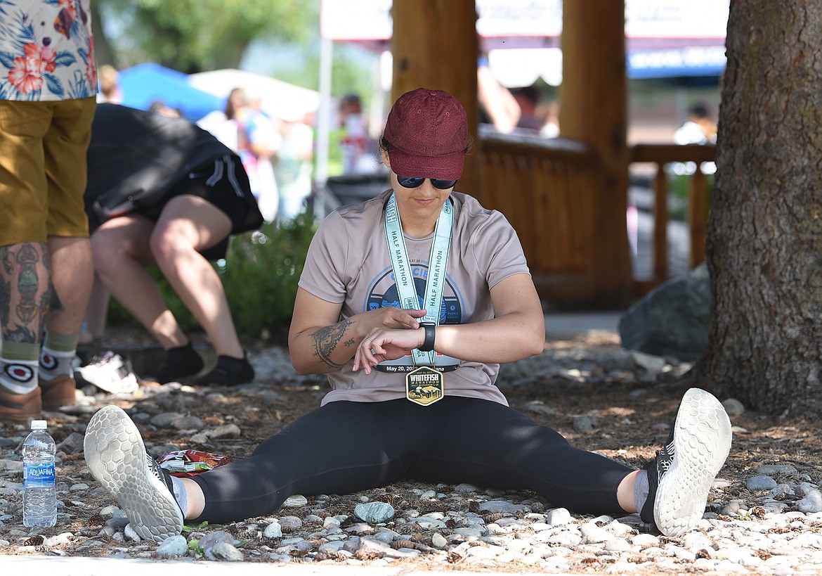 A racer checks her watch and rests in Depot Park after finishing a race at the Whitefish Marathon on May 20. (Julie Engler/Whitefish Pilot)