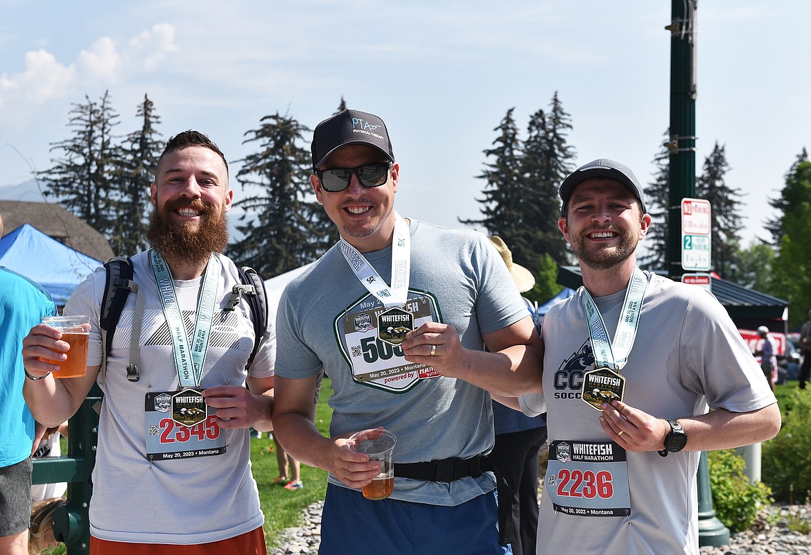 Three race finishers celebrate with their medals and a couple beers at the Whitefish Marathon. (Julie Engler/Whitefish Pilot)