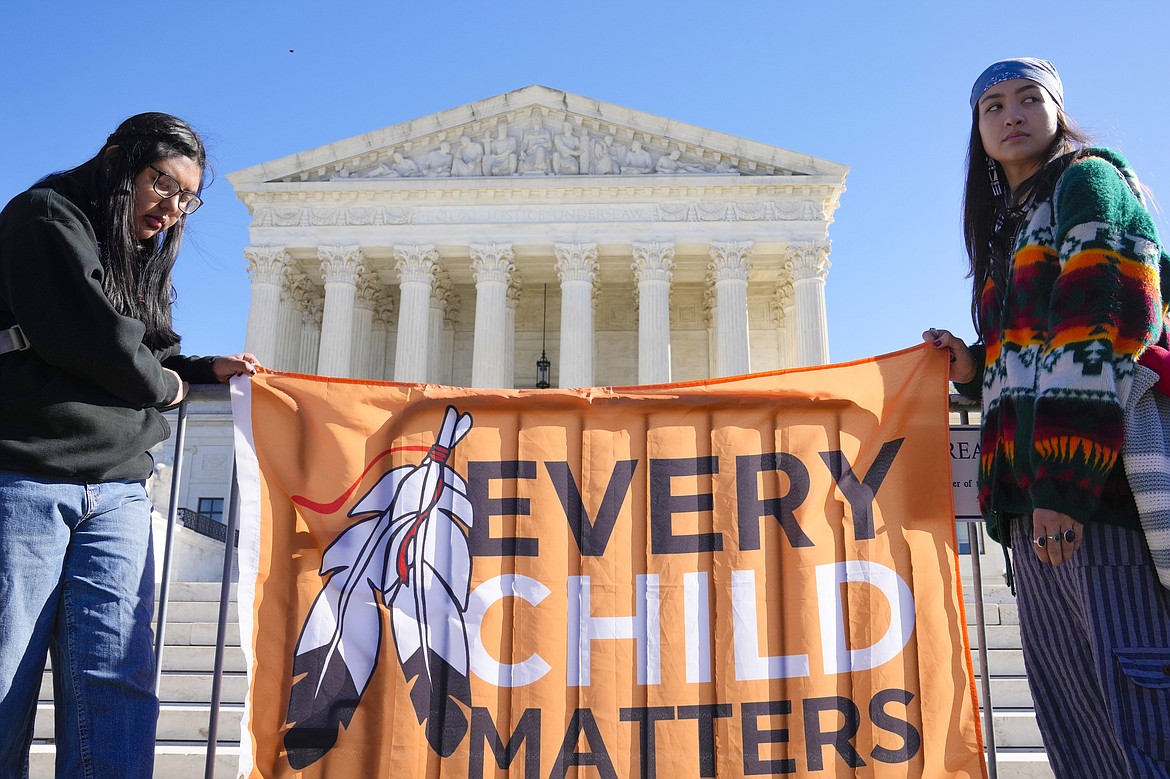 Demonstrators stand outside of the U.S. Supreme Court, as the court hears arguments over the Indian Child Welfare Act on Nov. 9, 2022, in Washington. Montana Gov. Greg Gianforte has signed into law legislation Monday, May 22, 2023, that gives Native American families preference in fostering and adopting Native children involved with child protective services, as the U.S. Supreme Court considers a case that could undercut a similar federal law. (AP Photo/Mariam Zuhaib, File)