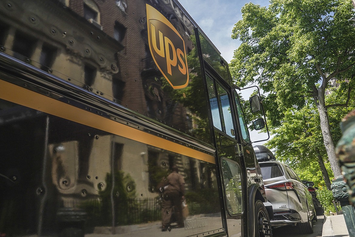 A UPS delivery driver wheeling a load of boxes is reflected on the truck on Friday, May 12, 2023, in New York. More than 340,000 unionized United Parcel Service employees, including drivers and warehouse workers, say they are prepared to strike if the company does not meet their demands before the end of the current contract on July 31. (AP Photo/Bebeto Matthews)