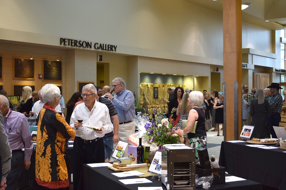 Attendees sip wine and check out the silent auction offerings at the silent auction at Cellarbration! Saturday evening. The event raised $167,000 for scholarships.