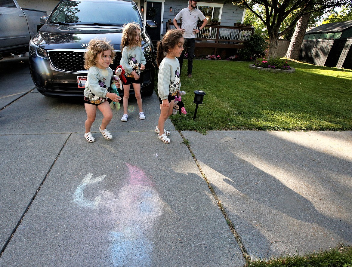 Camila Clark starts to run with the Ariel doll past an Ariel drawing on the sidewalk in front of her Coeur d'Alene home, as sisters Caroline and Cayden and dad Cody Clark look on.