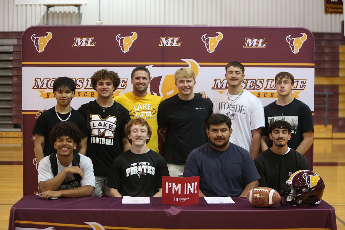 Surrounded by teammates and friends, Moses Lake seniors Iden Bone, front row middle left, and David Araiza, front row middle right, smile for photos at Araiza and Bone’s signing ceremony to play college football at Whitworth University.