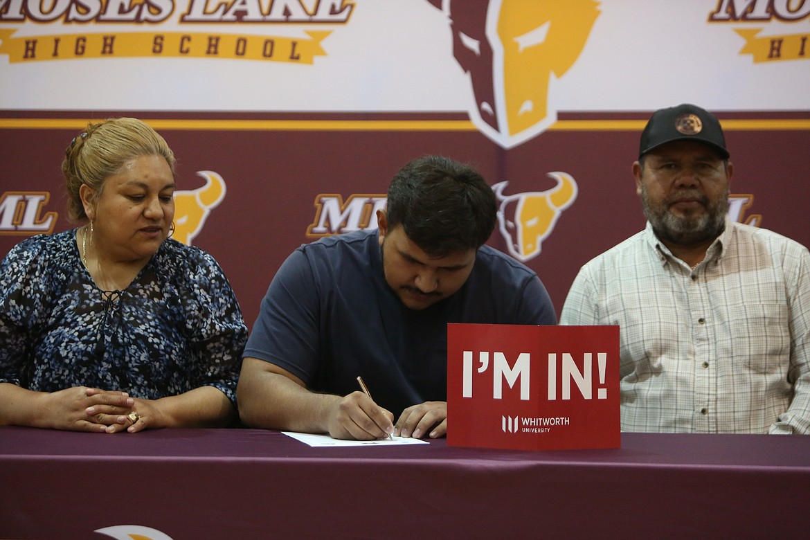 Moses Lake senior David Araiza, center, signs his national letter of intent to play college football at Whitworth. Araiza is signing as a left guard.