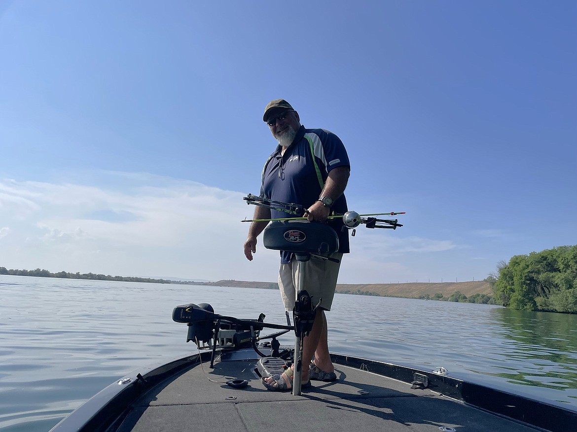 Ty Swartout stands on the bow of his bass fishing boat and prepares to shoot carp as the boat drifts along the shore of Moses Lake on May 20 during the Moses Lake Carp Classic.