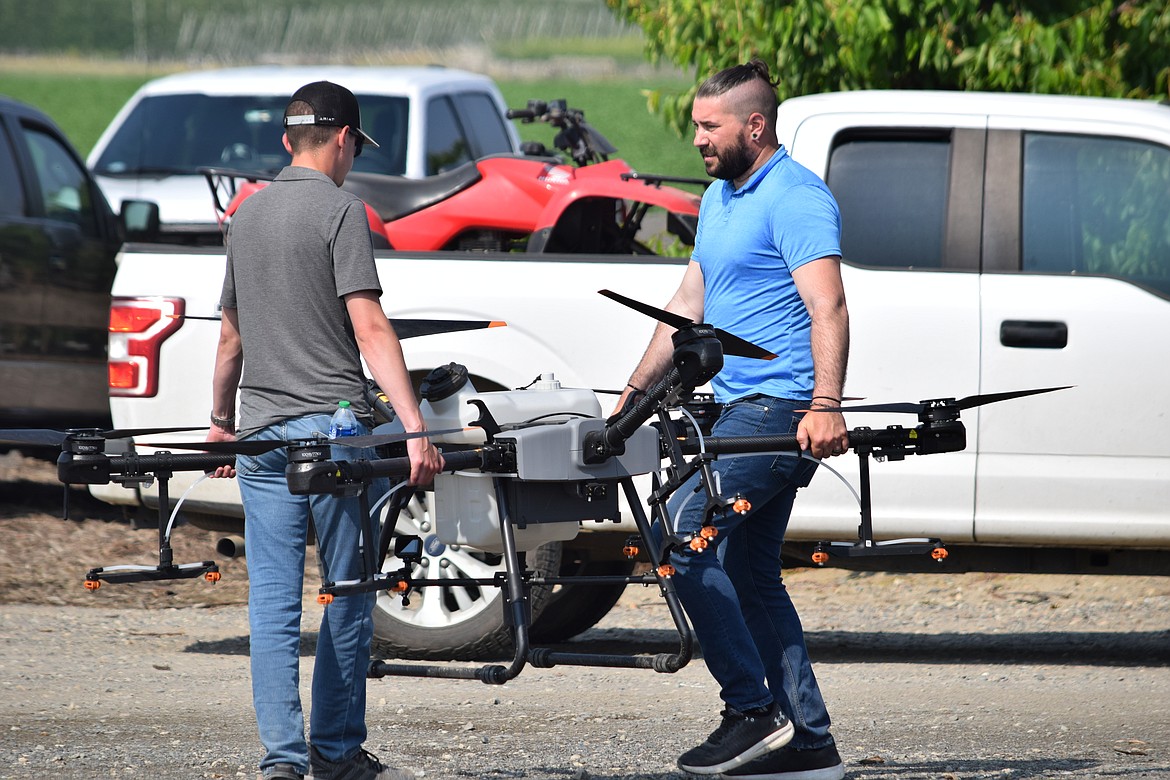 Michael Evans and Charlie Lautenbach of Altitude Agri Systems haul a DJI Drones T-30 in position for launch. The six-rotor drone can hold and disperse 30 liters of liquid and fly for up to 15 minutes.