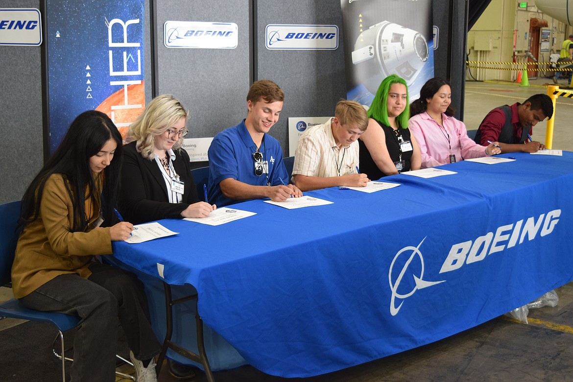 High school students Dahlia Al Hayyawi from Kamiakin High School in Kennewick, Aurora Beplate of Mead Senior High School in Spokane, Caleb Craddock of Okanogan High School, Carter Noftle of Royal High School, Martiza Gomez of Bridgeport High School, Adelia Ramirez of Kiona-Benton City High School, and Alexis Sanchez-Escobar of Tonasket High School all sign certificates of appreciation from Boeing as part of the company’s STEM Signing Day event at their main hangar in Moses Lake on Wednesday.