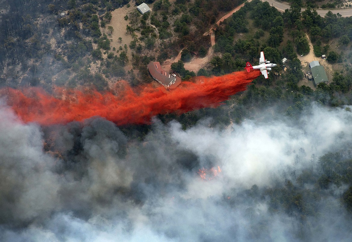 An aircraft lays down a line of fire retardant between a wildfire and homes in the dry, densely wooded Black Forest area northeast of Colorado Springs, Colo., on June 13, 2013. A federal judge said Friday, May 26, 2023, that chemical retardant dropped on wildfires by the U.S. Forest Service is polluting streams in western states in violation of federal law, but said it can keep being use to fight fires. (AP Photo/John Wark, File)