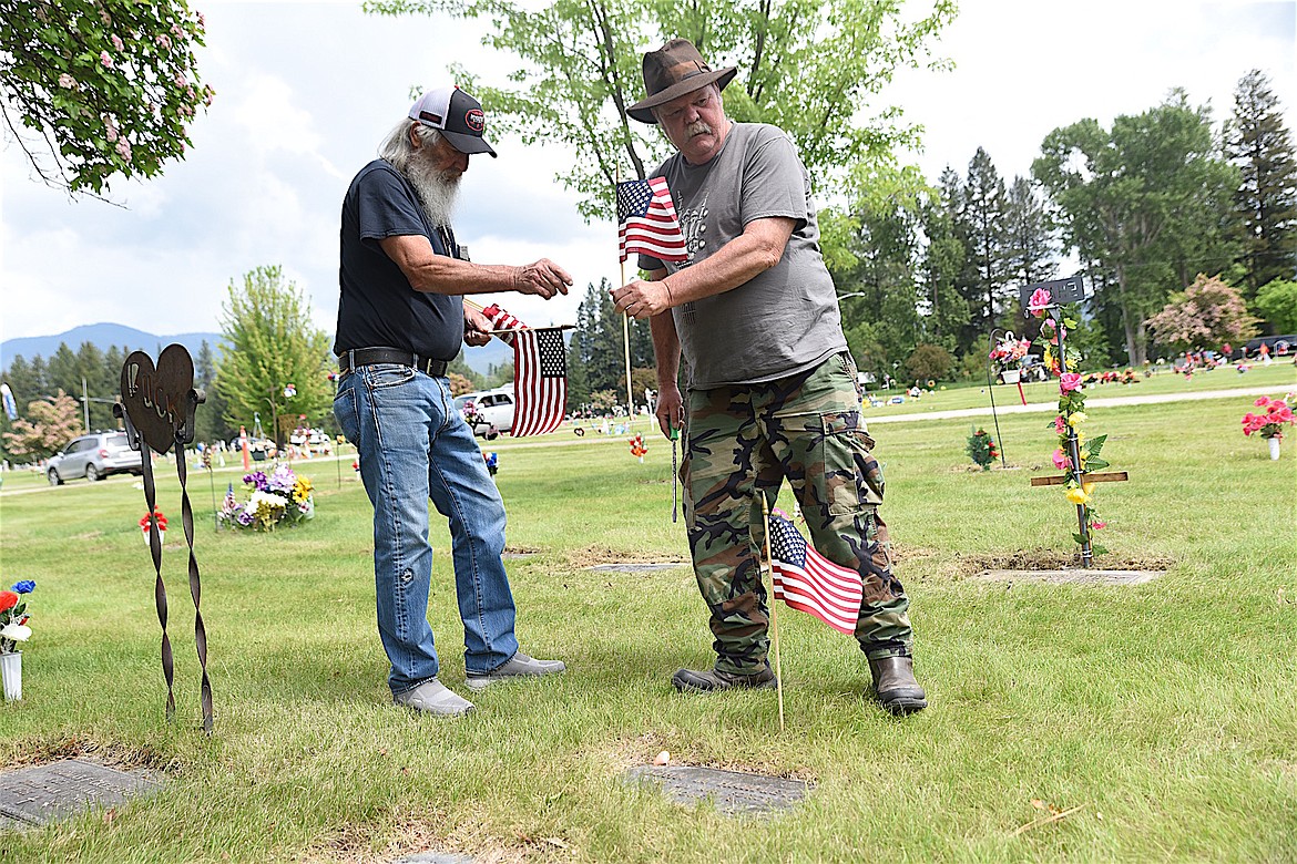 Randy Dempewolf, left, and Jerry Berreman place flags on the graves of Libby residents who served in the U.S. Armed Forces Saturday afternoon at Libby Cemetery in preparation for Memorial Day. (Scott Shindledecker/The Western News)