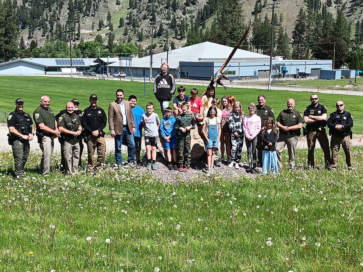 Superior fifth grade student Madisyn Allard, center in bib overalls, is this year’s winner in the Montana Law Enforcement Appreciation Poster Contest for Region 1. Attorney General Austin Knudsen made the presentation to Madisyn and her classmates with Montana troopers and the Mineral County sheriff and deputies. (Monte Turner/Mineral Independent)