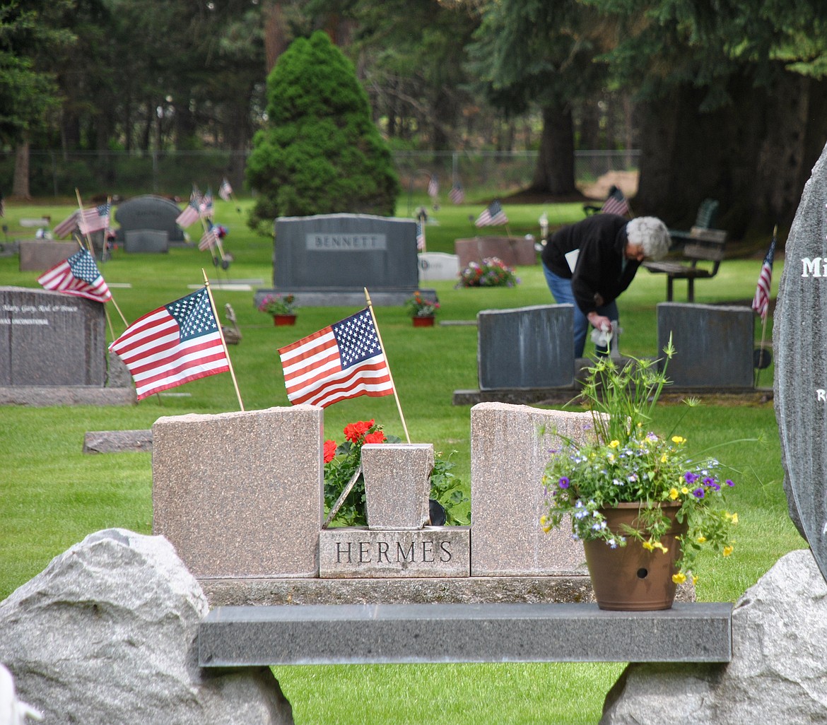 Marilyn Miller reverently cleans a grave marker at the St. Regis Cemetery over the Memorial Day weekend. (Amy Quinlivan/Mineral Independent)