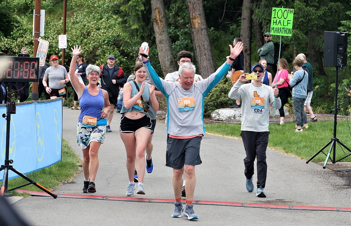 Bill Daniel, with family cheering for him, raises his arms at McEuen Park after finishing his 100th half marathon Sunday.