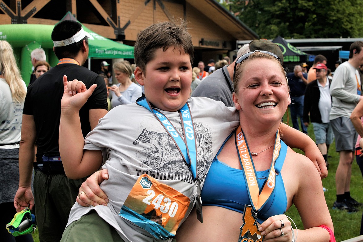 Tatyana Kido, who finished the Coeur d'Alene half marathon, holds her son, Bryce Kido, after he finished the 5K at McEuen Park on Sunday.