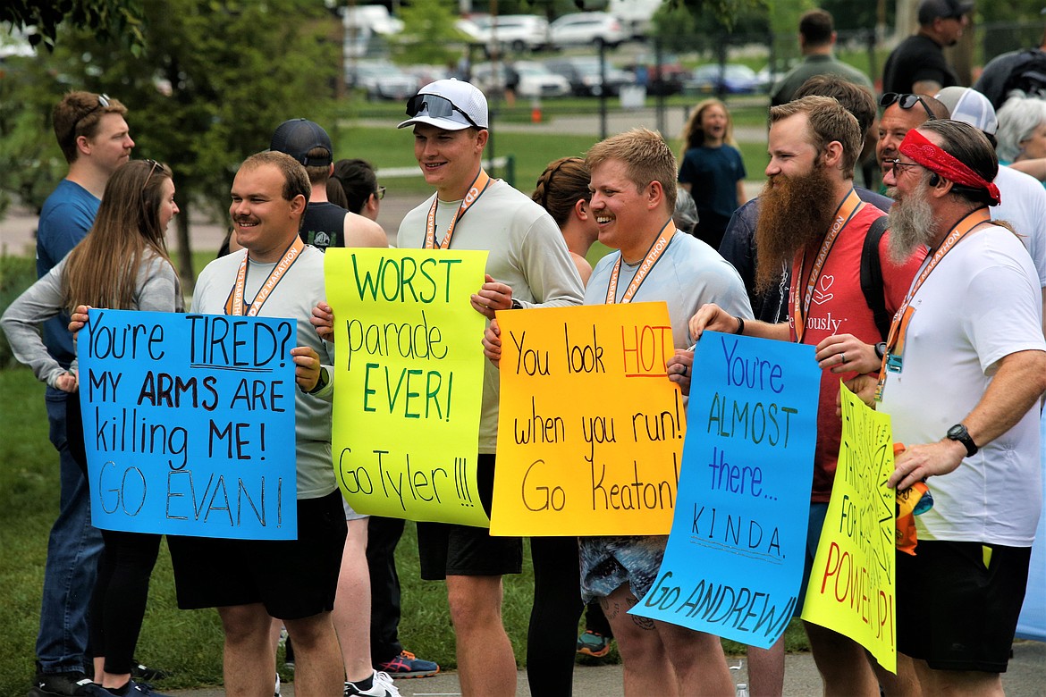 Runners hold signs at the finish line of the Coeur d'Alene Marathon, Half Marathon, 10K and 5K at McEuen Park on Sunday.