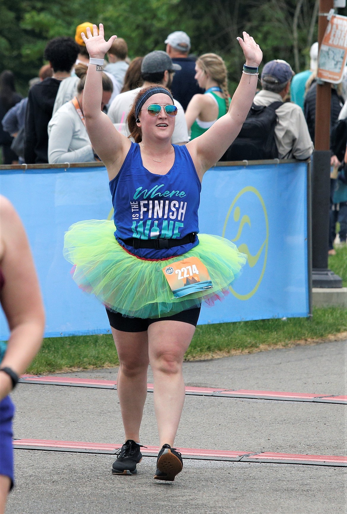 Kristian Enghusen of Spokane raises her arms in triumph at the finish line of the 5K at McEuen Park on Sunday.