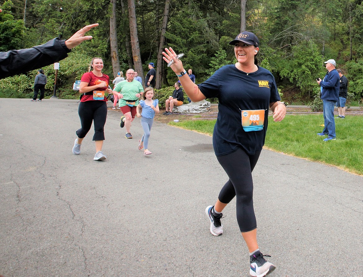 Chelsea Keogh of Coeur d'Alene waves as she nears the finish line of the Coeur d'Alene half marathon at McEuen Park on Sunday.