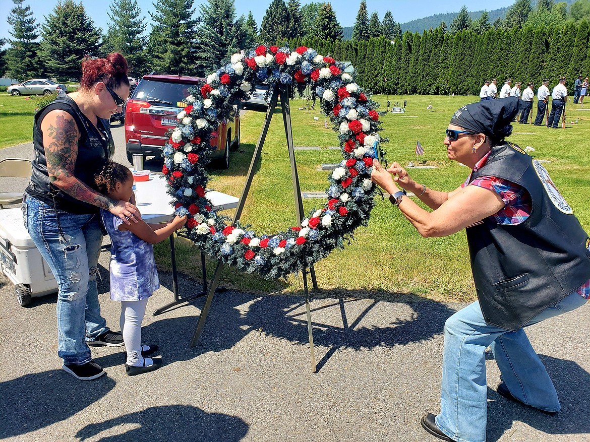 Northwest Guardian Riders take pictures as a little girl places a poppy, a reminder of the living legacy of fallen service members, in a wreath at the Rathdrum Memorial Day celebration at Pinegrove cemetery Monday.