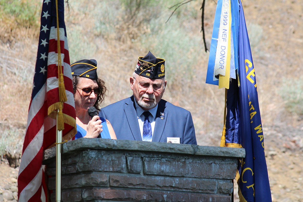 Kimberly Thomas, commander of American Legion Post 28, Ephrata, reads the names of service members commemorated on the flags that make up the Aisle of Flags at the Ephrata Cemetery. Mike Montenay, former post commander, right, gave a short speech during the remembrance ceremony Monday. Montenay said each flag in the Aisle of Flags had draped the coffin of the veteran and was donated by family members.