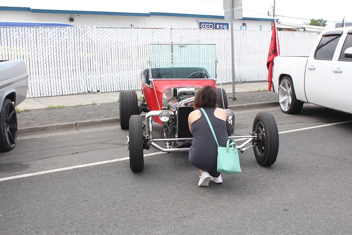 A bystander gets down for a close look at a car.