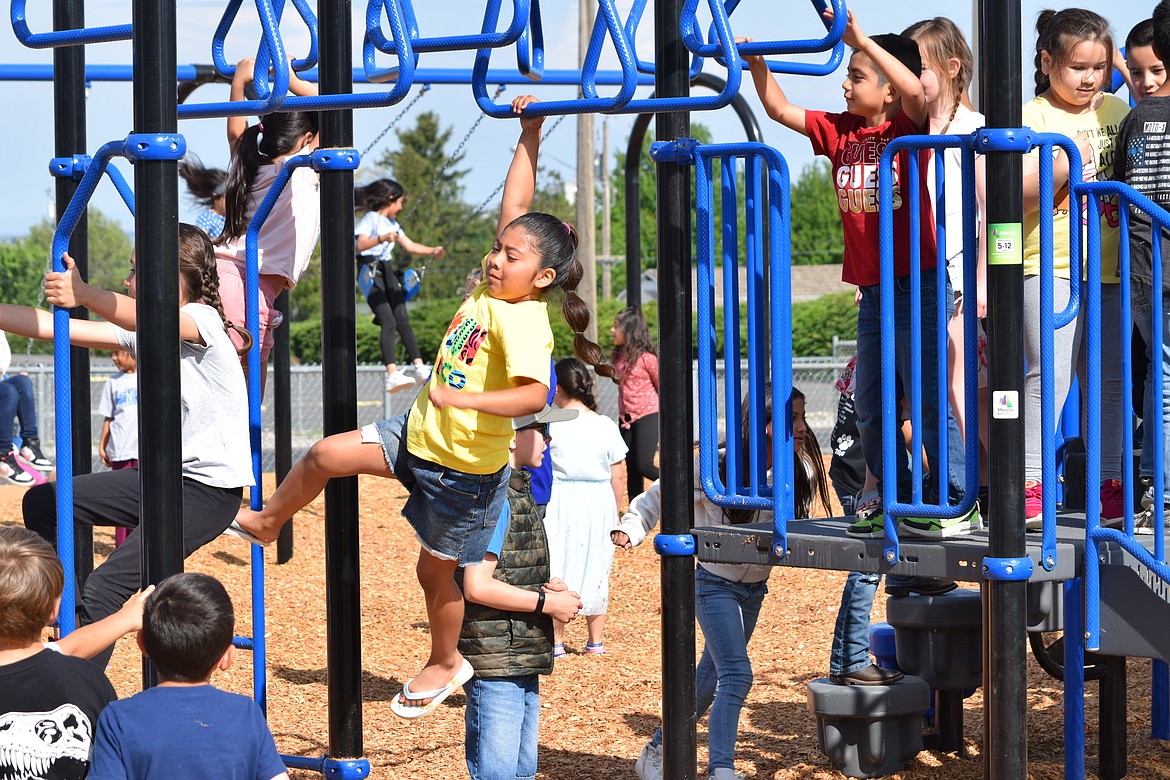 A girl hangs on the monkey bars on one of Warden Elementary School’s two new playground sets Friday morning.