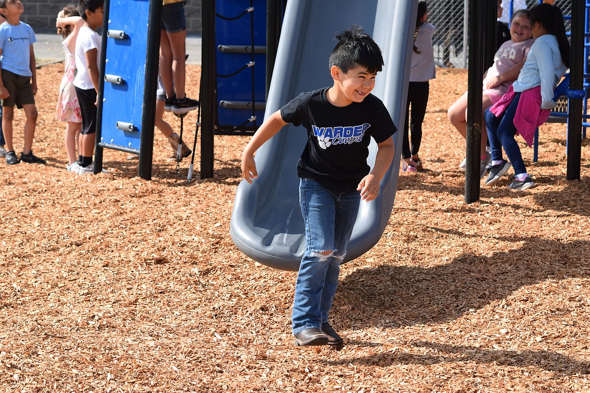 A student smiles after sliding down one of the new slides at Warden Elementary School on Friday.