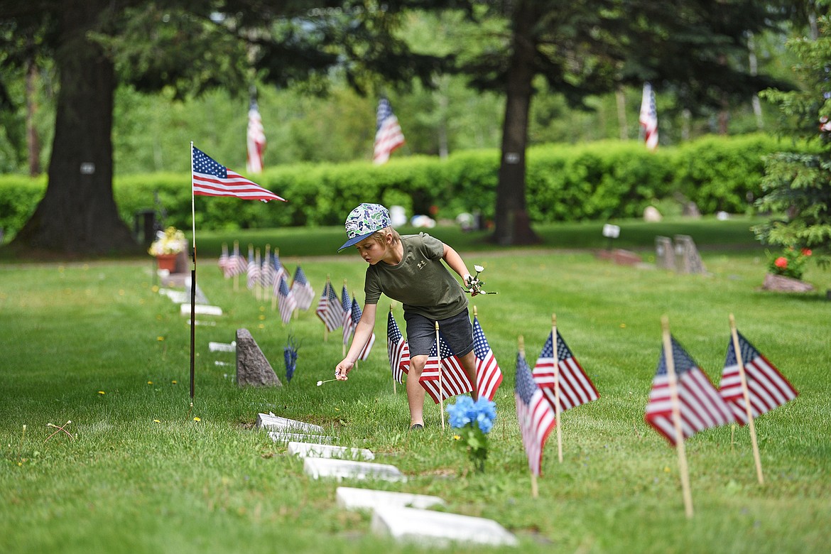 A youngster places white flowers on veteran's graves Monday at the Whitefish City Cemetery. (Julie Engler/Whitefish Pilot)