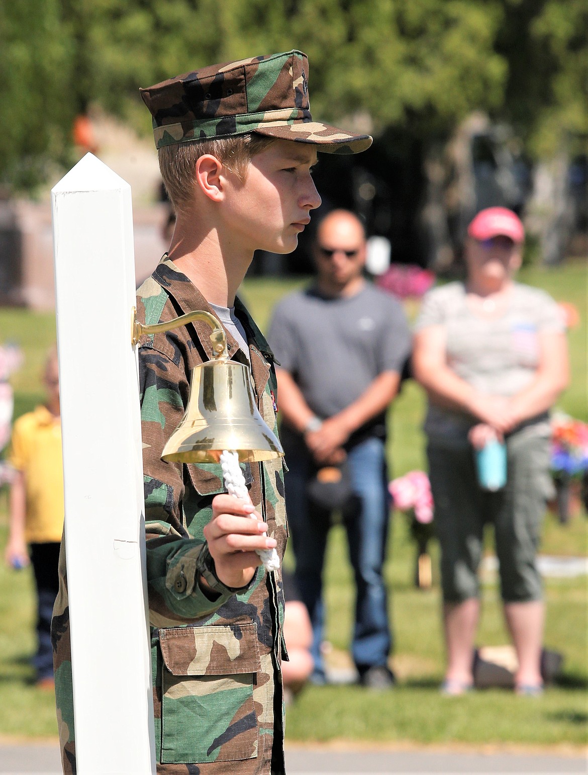 Young Marine Nathan Holt rings the bell during the Memorial Day ceremony at Coeur d'Alene Memorial Gardens.