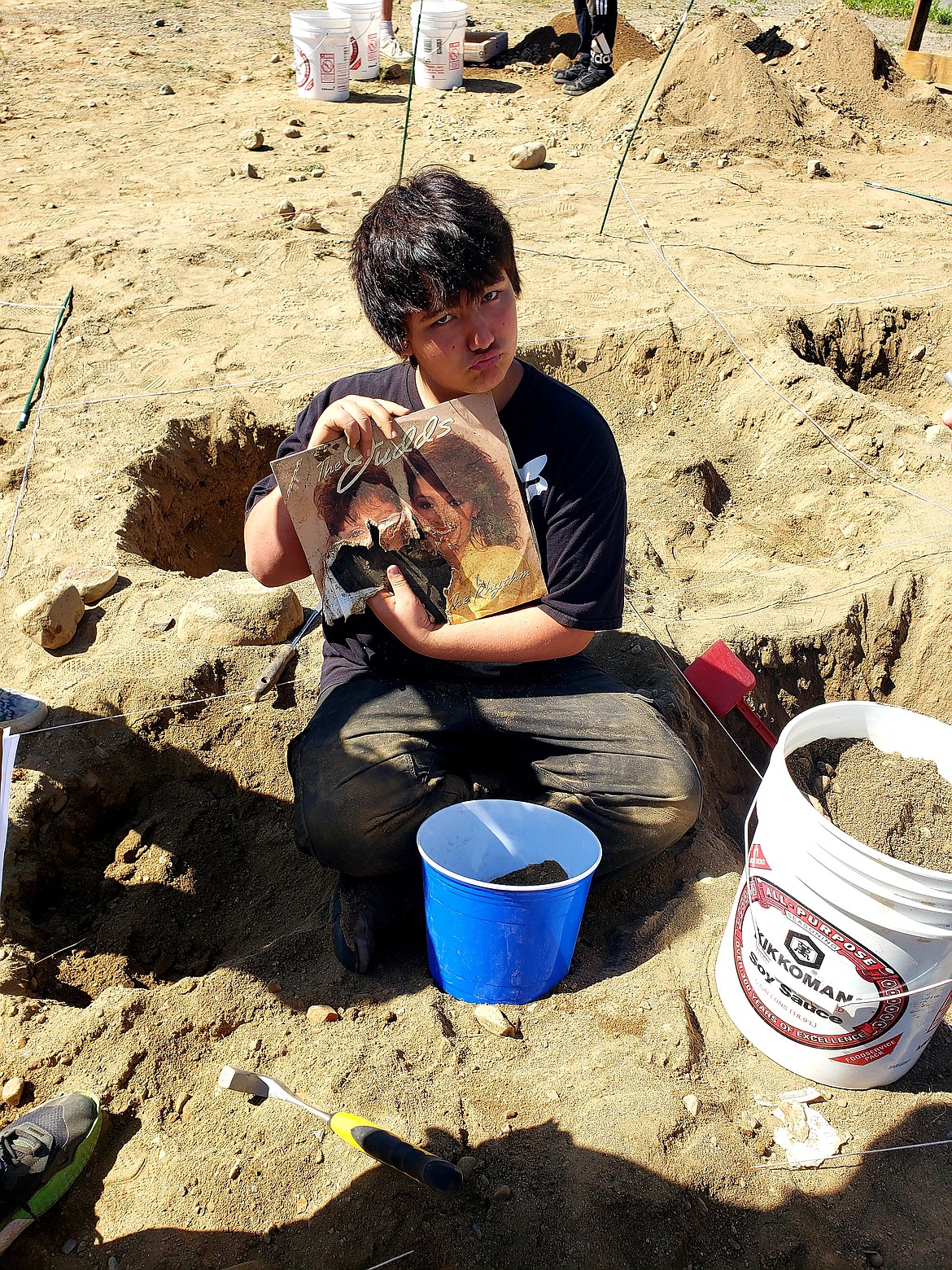 Eighth grader Geir Hull holds up an album he found while digging in an archeological plot at Timberlake Middle School Tuesday.