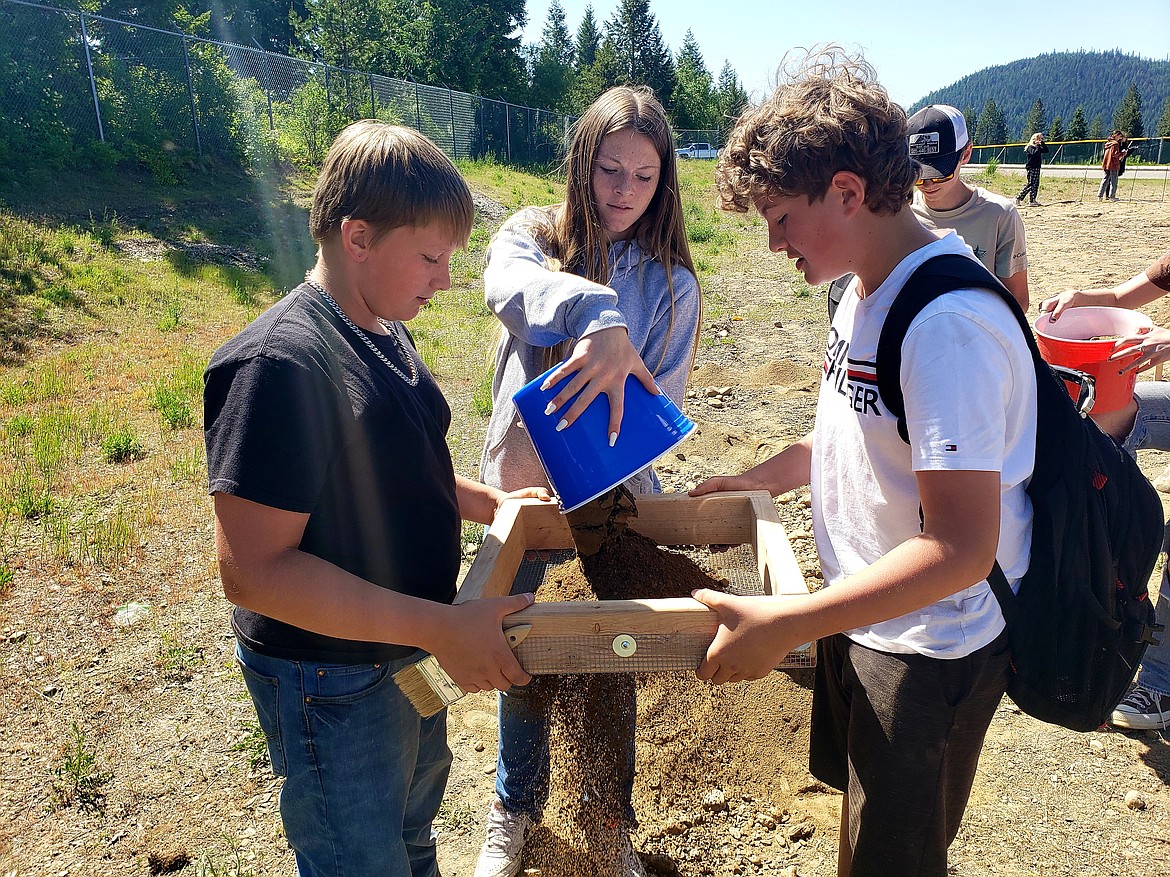 From left, Seventh grade Timberlake students Blake White, Brooke Hell and Carter Hilliard sift dirt in search of buried treasure during a school-wide archeological dig Tuesday.
