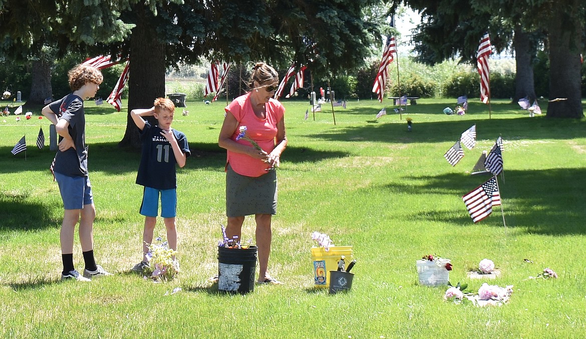 Carla McKean, right, and her grandsons London McKean, left, and Nehemiah McKean lay flowers on the graves of Carla McKean’s parents and grandparents at Pioneer Memorial Gardens Monday.