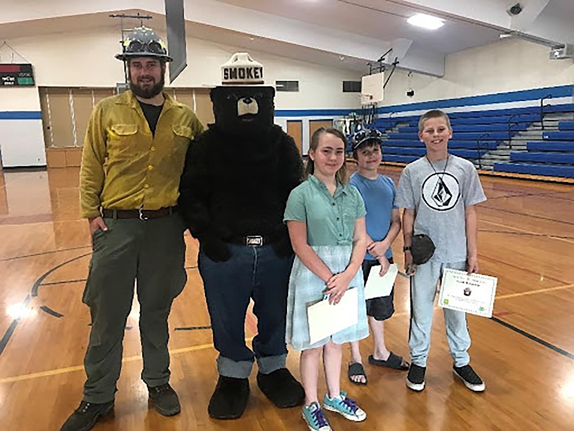 Priest River Elementary fourth-grade poster contest winners Sienna Rader, Trent Souders, and Caleb Runnfeldt pose with Smokey Bear along with Priest River Elementary graduate and U.S. Forest Service firefighter Conrad Ahlers.