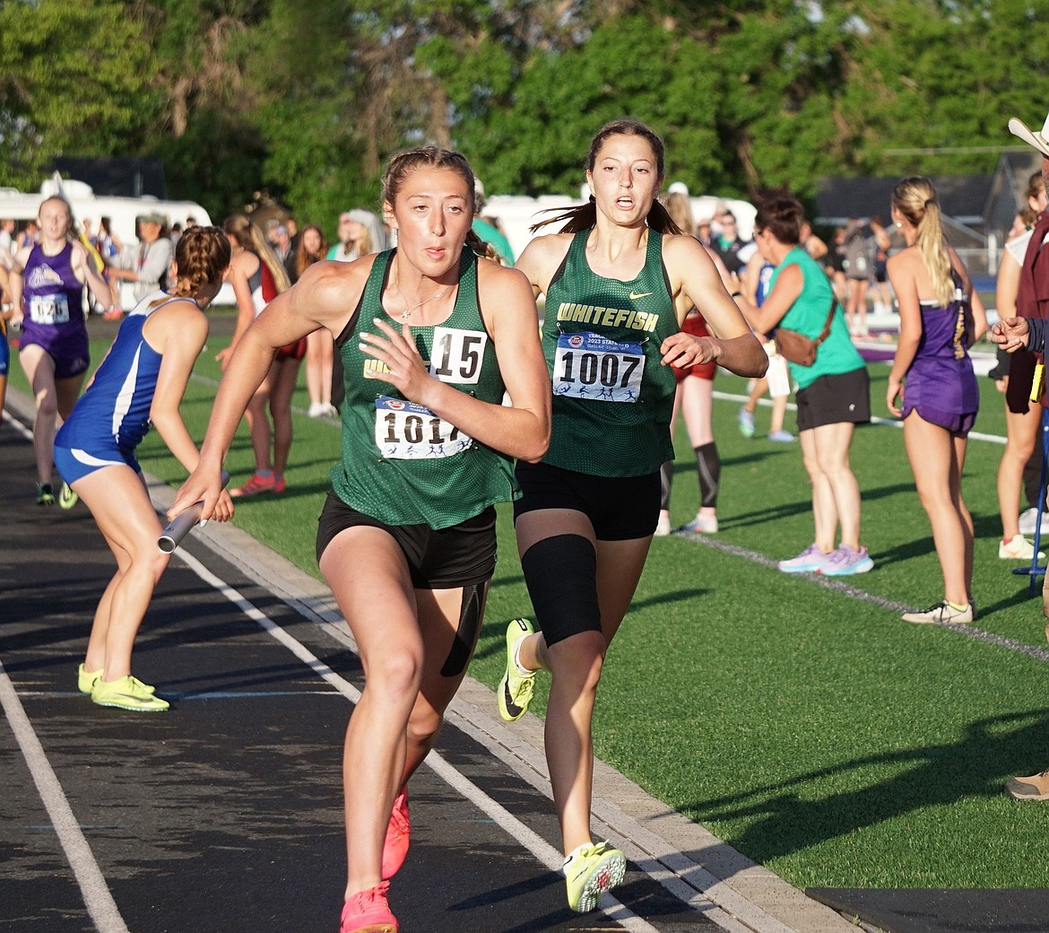 Brooke Zetooney (left) sprints away after receiving the baton from teammate Hailey Ells at the final event of the State Meet. The Whitefish squad easily defeated their nearest competitors completing the relay in 4:00.71, nearly seven seconds ahead of their rivals. (Matt Weller photo)