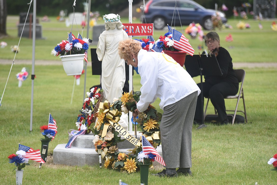 Austin Reedy Post 97 American Legion Auxiliary member Adrene Adams places an American Gold Star wreath at the Angel statue in Libby Cemetery on Sunday, May 28. (Scott Shindledecker/The Western News)