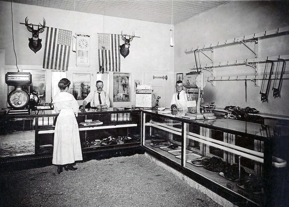 In the City Meat Market photograph, Tom Nicholson attends to a customer, and Frank Zimmerman is behind counter on right (circa 1916). Note: Look at the reflection in the mirror attached to the front of the counter. You can see the feet of the photographer.