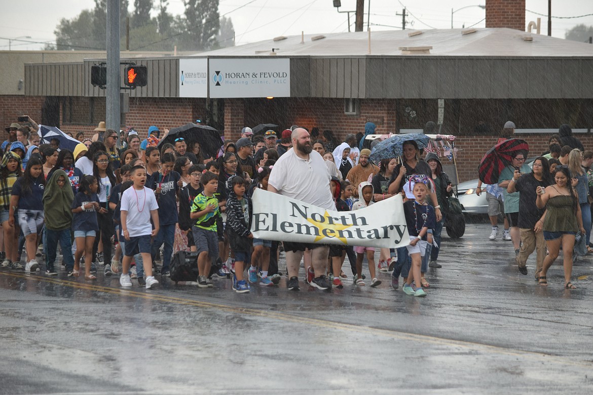 Students, staff, faculty and parents from North Elementary School parade in the rain down Third Avenue to Frontier Middle School during the Kiddie Parade on Saturday, part of the city’s annual Spring Festival Celebration.