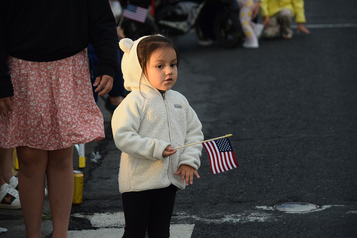 A girl holding a tiny flag stands on the side of Third Avenue waiting for the start of the Grand Moonlight Parade on Saturday.