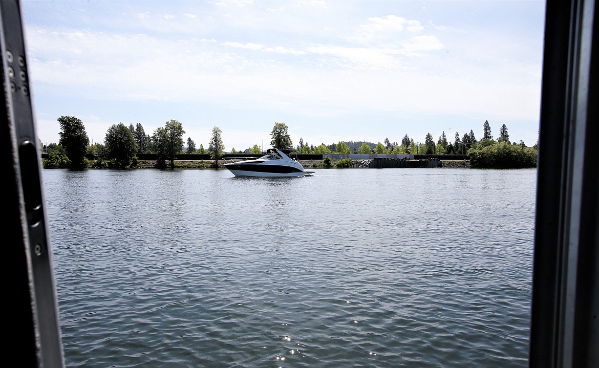 A boat glides past a Kootenai County Sheriff's Office marine patrol unit on the Spokane River on Wednesday.