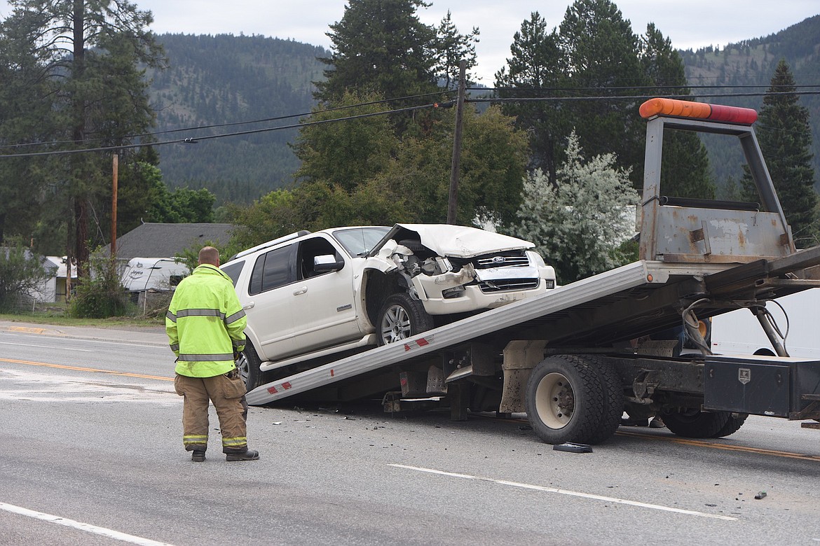 A Libby Volunteer Fireman watches a Ford Explorer being lifted on to a tow truck Thursday morning after a 3-vehicle traffic accident on U.S. 2, just east of Libby. One woman was taken by Libby Volunteer Ambulance to the hospital. (Scott Shindledecker/The Western News)