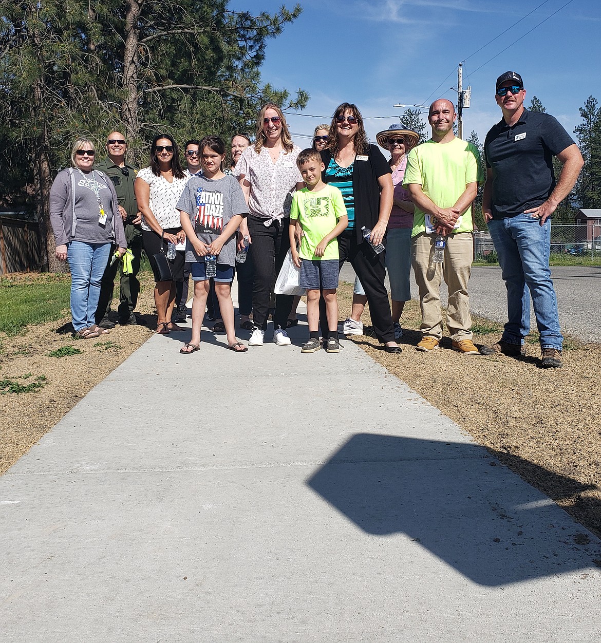 Athol city staff, children, parents and residents stand on the first sidewalk built in the city during a ribbon cutting and walkabout Thursday. Hopefully the sidewalk will be the first of many connecting the streets through town.