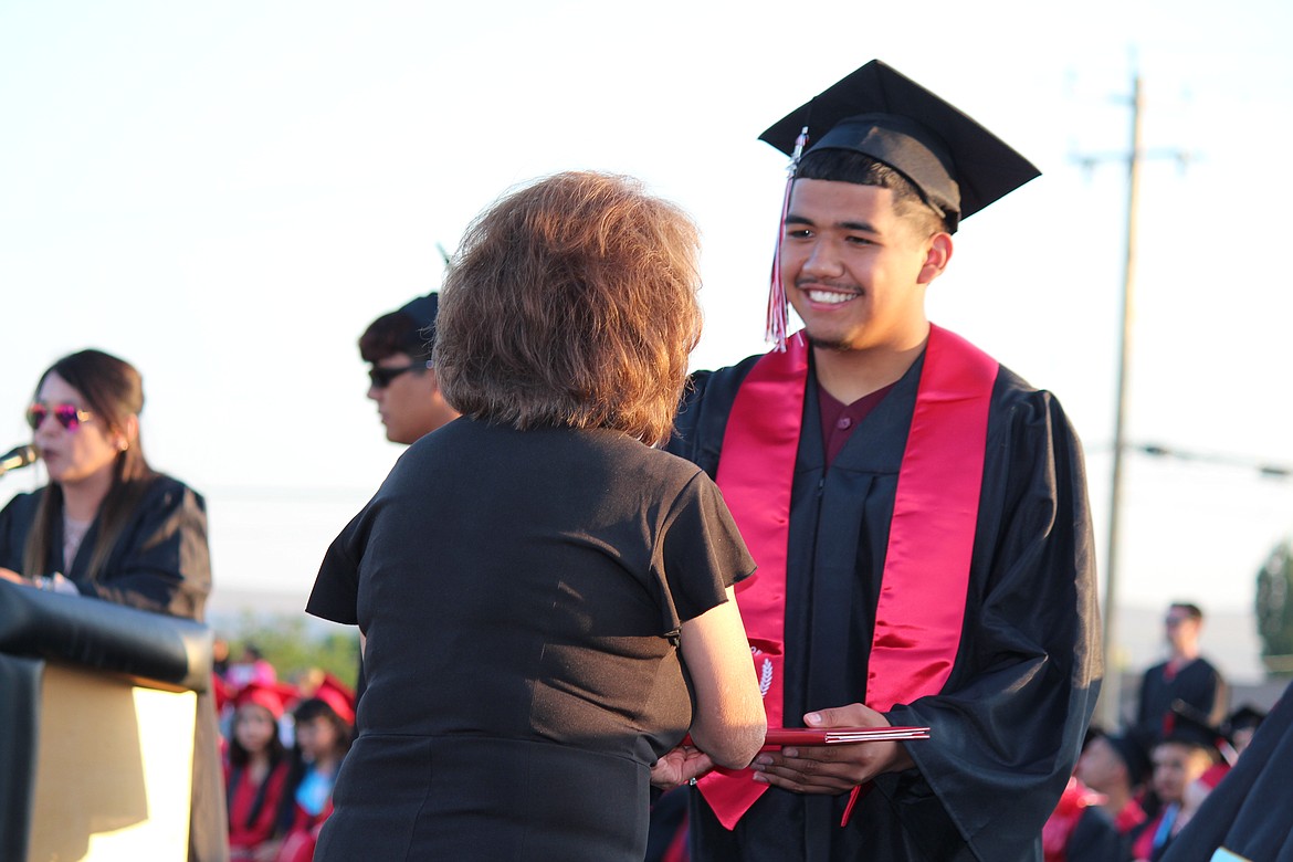 A member of the Othello High School class of 2023, right, receives his diploma from Othello School Board member Sharon Schutte. Graduation ceremonies for the senior class, about 270 strong, filled Huskie Stadium with family and friends who cheered them on.